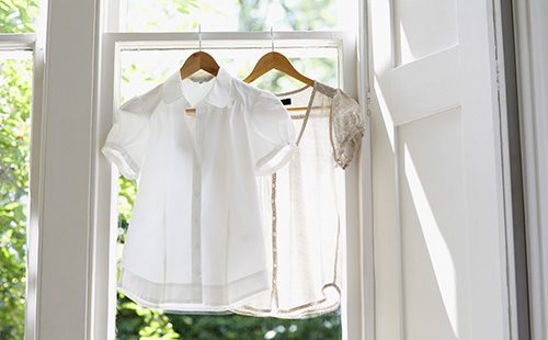 Белые блузки висят у открытого окна