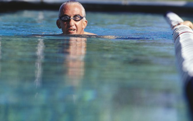 мужчина в очках плывет в бассейне