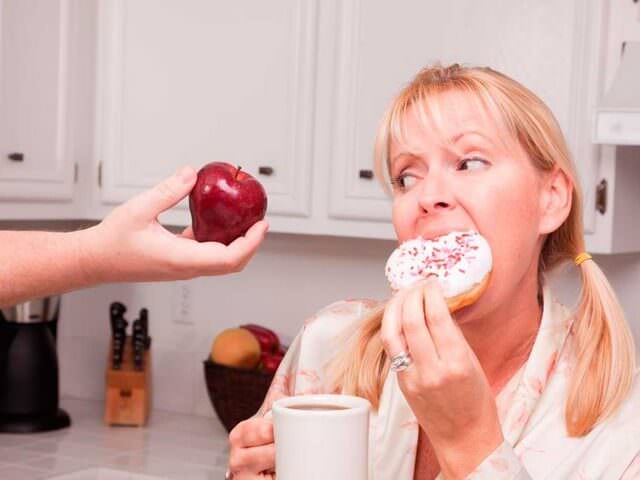 Женщина кушает пончик